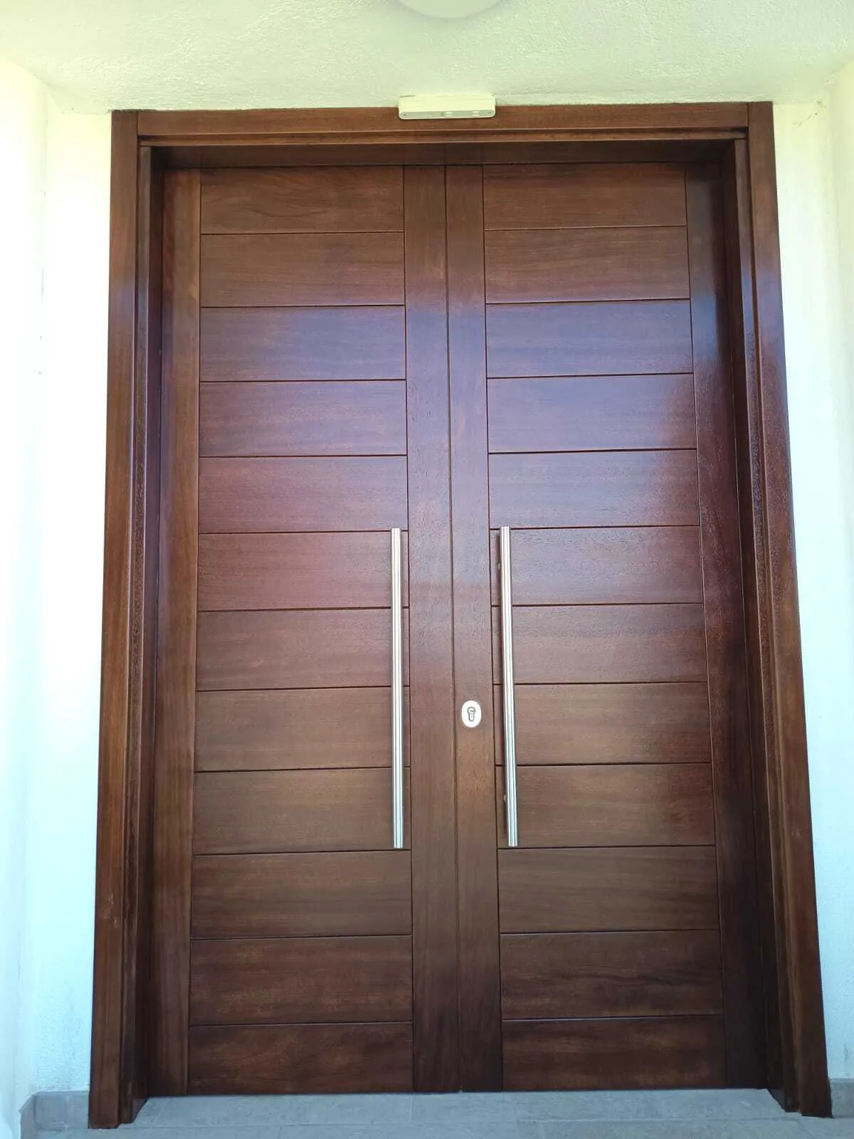 Puerta de entrada de madera restaurada y barnizada por Felrubi en Rubí